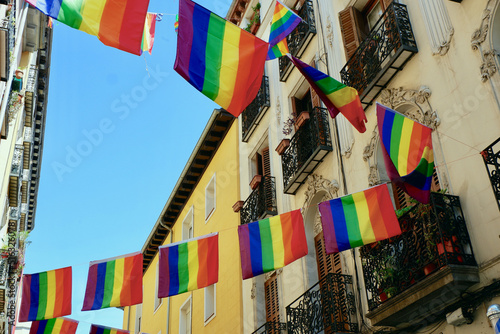 Festive flags of LGBTQ community hang between elegant retro buildings in gay friendly district Chueca in Madrid, Spain photo