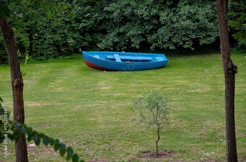 old blue rowboat on a green grass field