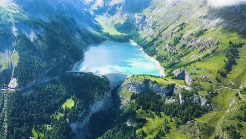 Water dam and reservoir lake aerial drone footage in green Swiss Alps mountains generating hydroelectricity. Low CO2 footprint, decarbonize, renewable energy, sustainable development. 4K 60fps video.