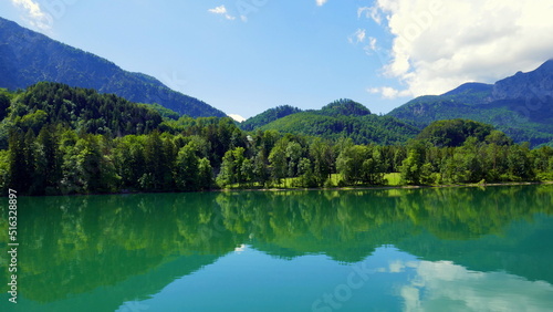 schöner Blick auf Ufer des Kochelsees in Bayern mit Badestrand, Berg, Wald, blauem Himmel und Wolken