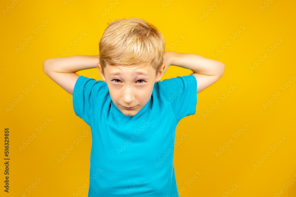 boy in a blue t-shirt on a yellow background raised his hands above his head boy in a blue t-shirt on a yellow background raised his hands above his head