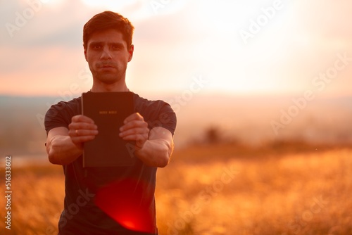 Billede på lærred Human praying on the holy bible in a field during beautiful sunset