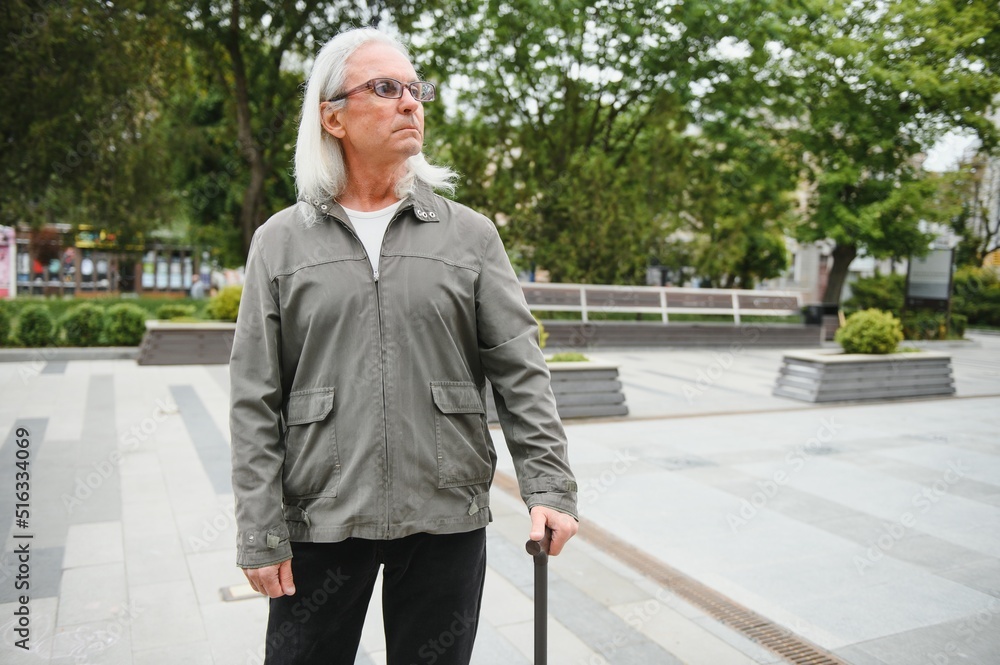 Portrait of senior man holding walking stick while resting in park. Portrait of senior man holding walking stick while resting in park.