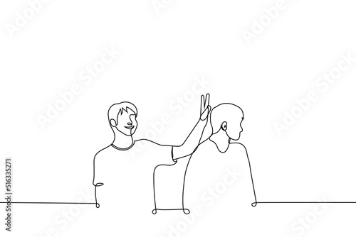 man building horns to his friend - one line drawing vector. concept of friendly joke, playfulness between friends