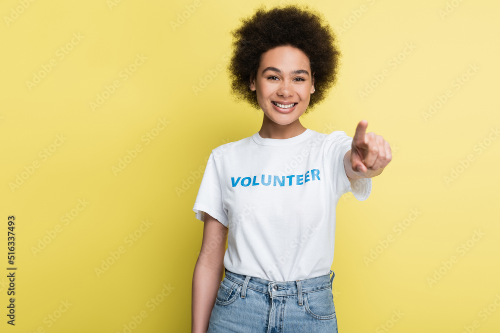 joyful african american volunteer pointing with finger at camera isolated on yellow. joyful african american volunteer pointing with finger at camera isolated on yellow.
