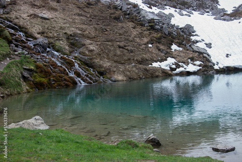 Crystal clear body of water near the rocky shore covered with snow photo