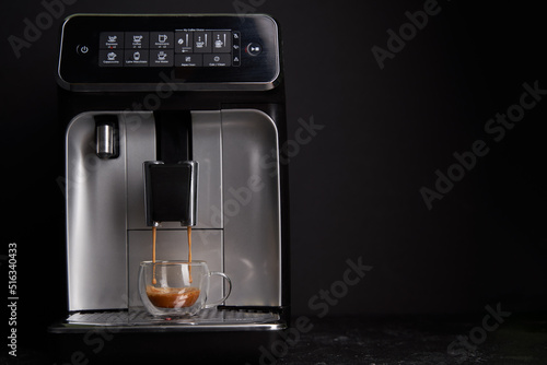 Freshly brewed coffee is poured from the coffee machine into glass cups.