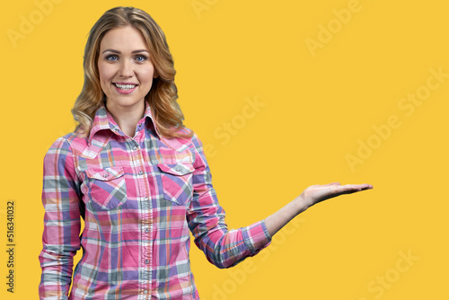 Happy smiling woman showing something with hand on color background. Promotion concept.
