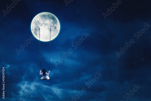 Little girl sit on the swing while hanging on moon