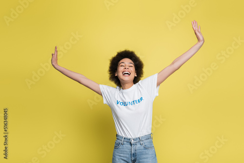 excited african american volunteer with outstretched hands and closed eyes isolated on yellow.