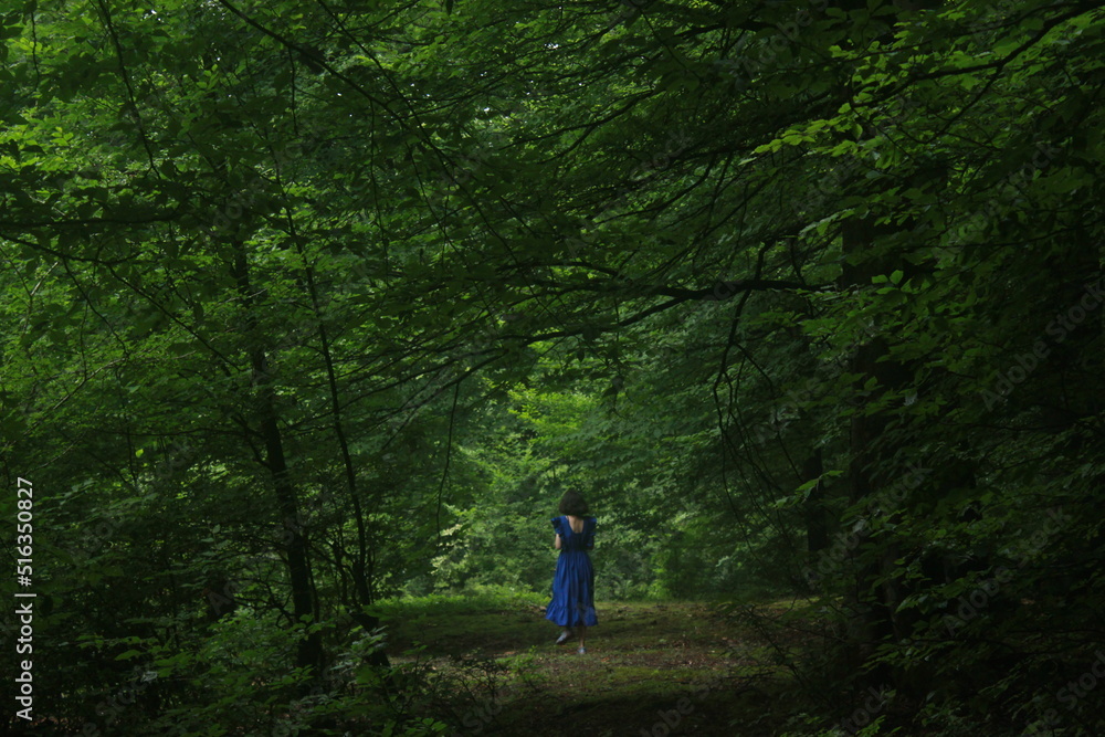 girl in a blue dress walking in forest