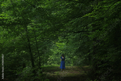 girl in a blue dress walking in forest