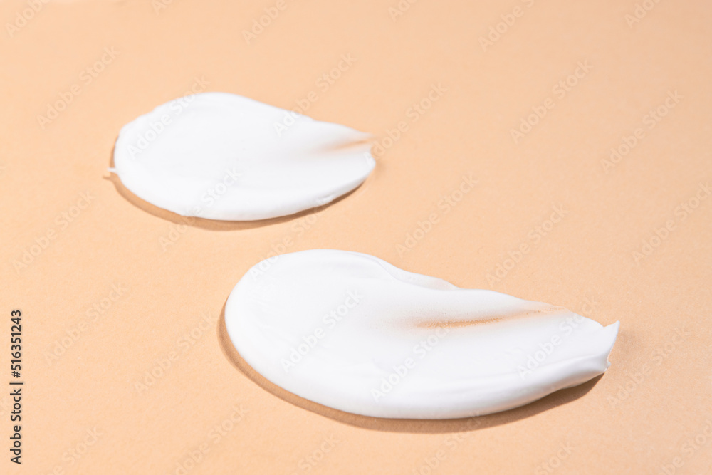 Smears of white cosmetic cream on a beige background. Beauty product for skin care sample top view. Smears of white cosmetic cream on a beige background. Beauty product for skin care sample top view.