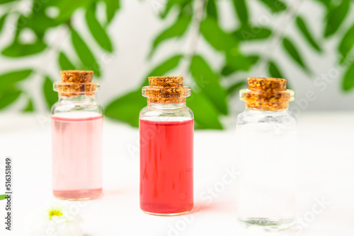 Glass bottles with colorful floral liquid for aromatherapy and perfumery. Herbal medicine, beauty product from natural ingredients.