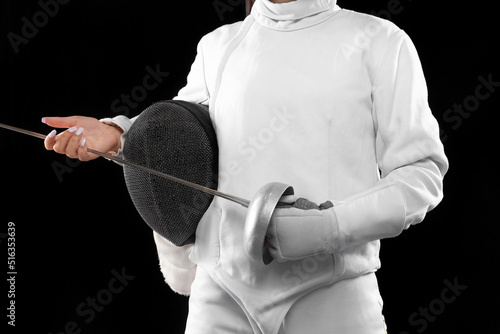 Closeup female fencer's body in white fencing costume with mask and rapier isolated on dark background. Sport, youth, activity, skills, achievements, goal.