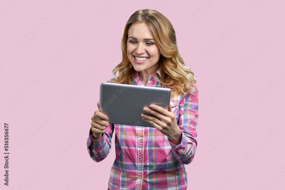 Young happy woman talking via internet on color background. Pretty caucasian girl using digital tablet on pink background. Young happy woman talking via internet on color background. Pretty caucasian girl using digital tablet on pink background.