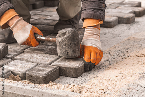 Laying paving slabs close-up. Road surface, construction. Sidewalk repair. Worker laying stone paving slab. Laying tiles in the city park garden . Manual fixed tessellated paving slabs