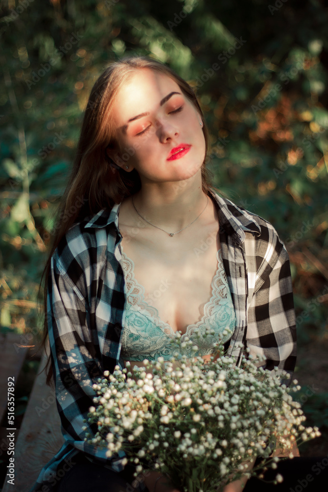 A cute woman with a bouquet of wildflowers under the sun's rays. Portrait in nature A cute woman with a bouquet of wildflowers under the sun's rays. Portrait in nature