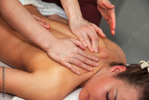 Two massaging therapist makes massage back for woman. Massage in four hands in SPA salon