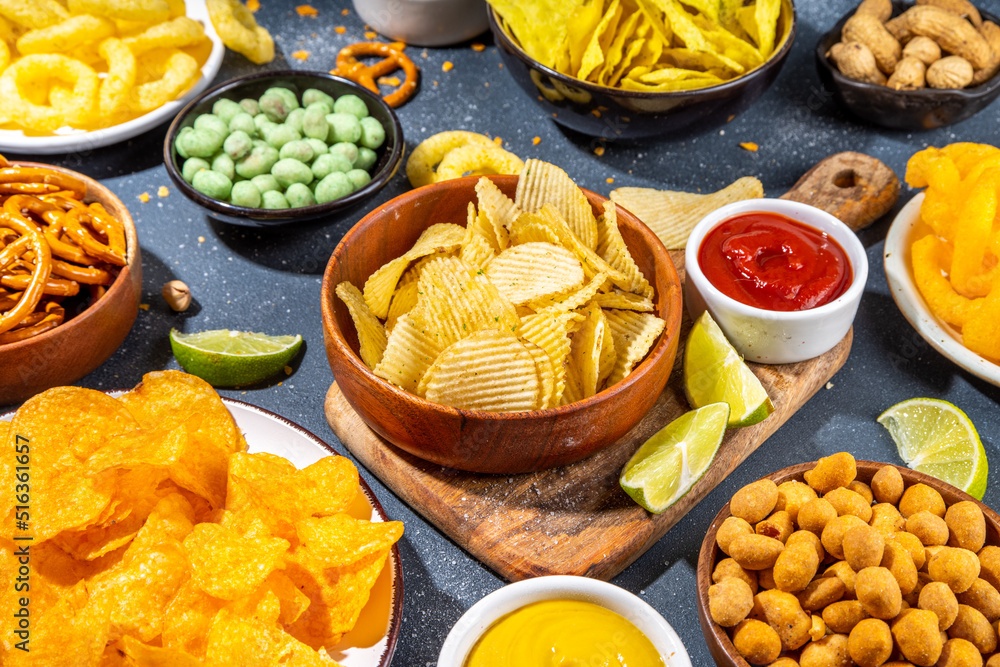 Various unhealthy salty bar snacks set. Dark grey table background with