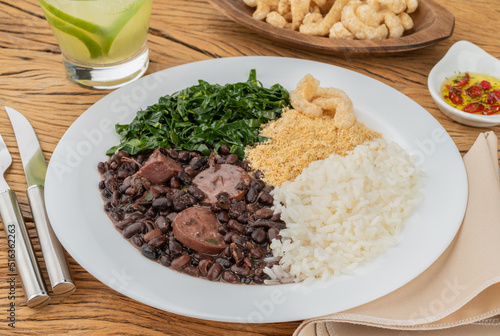 Typical brazilian feijoada with rice, pepper, farofa, kale, caipirinha and cracklings