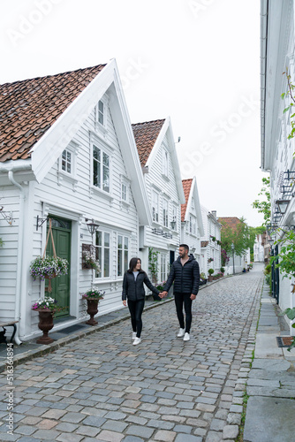 Young couple walking along a street in Stavanger with typical Scandinavian white houses in Norway. © Jenni Ventura Martil