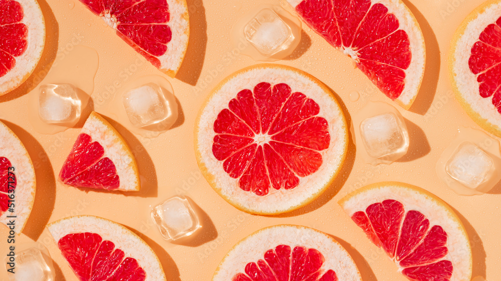 Grapefruit slices and melting ice cubes with harsh shadows background. Minimal concept, summer background, banner size Grapefruit slices and melting ice cubes with harsh shadows background. Minimal concept, summer background, banner size