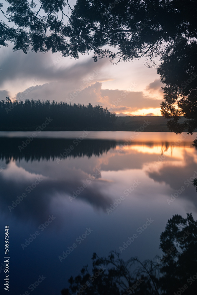 Fototapeta premium Serene view of a lake during sundown captured using long exposure with perfect reflection