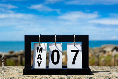 May 07 calendar date text on wooden frame with blurred background of ocean.