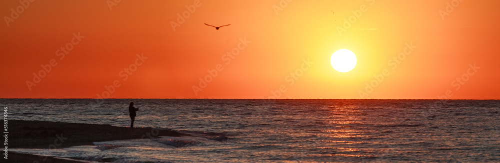 Majestic and dreamy sunset over sea and sandy beach with romantic silhouettes of couple in love