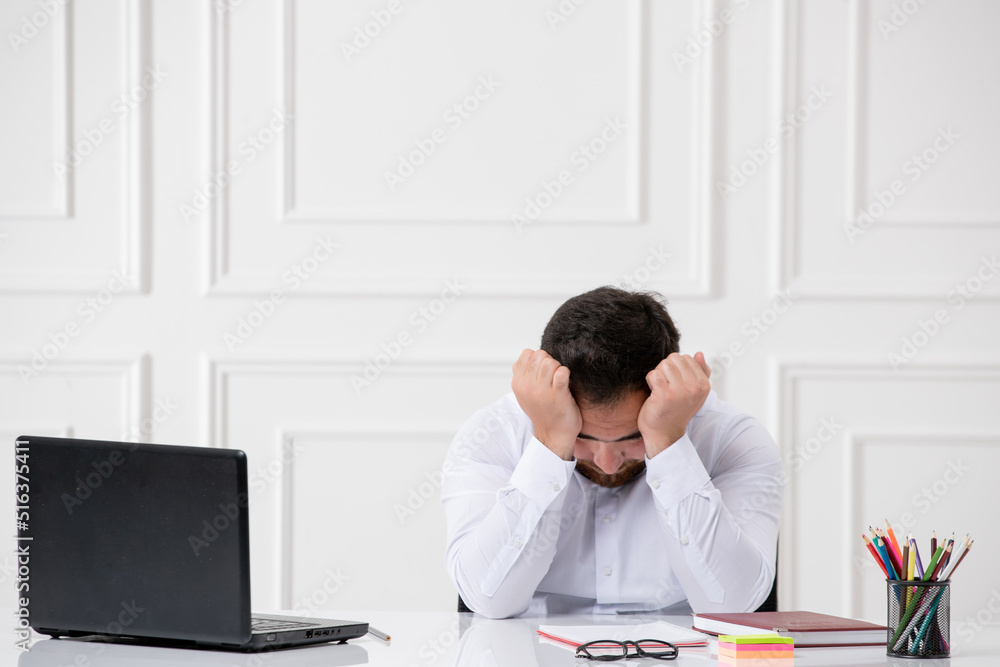 Fototapeta premium ADHD office cute young worker at work behind the desk with the computer tired holding head
