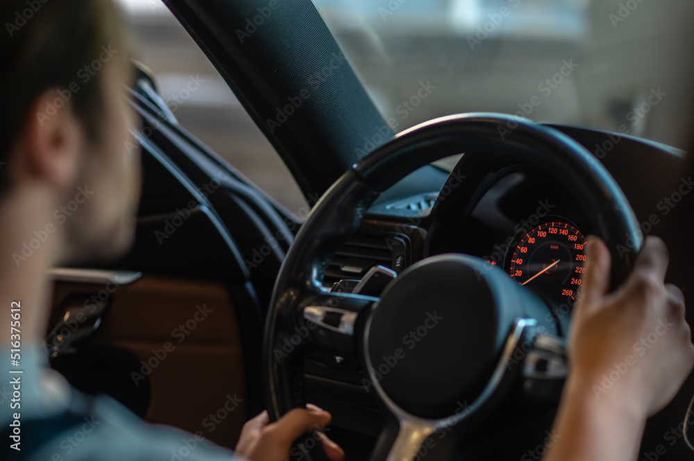 Young auto repair shop worker sitting in a car salon for car inspection Young auto repair shop worker sitting in a car salon for car inspection