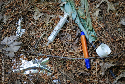 Trash littering the ground in the forest left behind by unscrupulous humans. The environmental impact of addiction, drug and alcohol use.