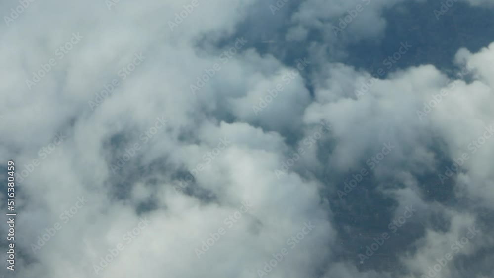 Flying among fluffy white clouds with a view of the land below them. Flying among fluffy white clouds with a view of the land below them.