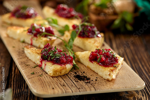 Hot appetizer for wine - grilled halloumi cheese with jam. Cheese appetizer baked halloumi on wooden background on rustic style. Adyghe cheese with berries dip on wooden table. photo