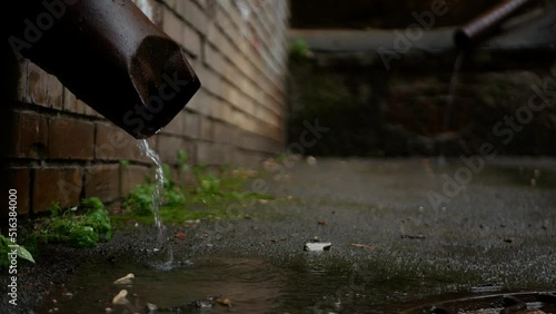 Water flows from old rusty gutters during rain. photo