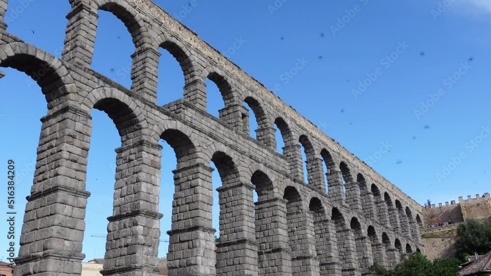 Segovia's Roman aqueduct full of swallows flying through the sky on a sunny day. Segovia's Roman aqueduct full of swallows flying through the sky on a sunny day.