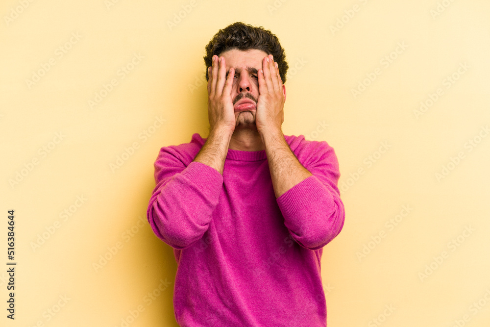 Young caucasian man isolated on yellow background whining and crying disconsolately. Young caucasian man isolated on yellow background whining and crying disconsolately.