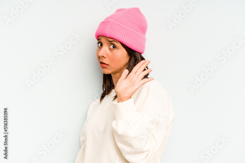 Young hispanic woman isolated on blue background blink through fingers frightened and nervous.