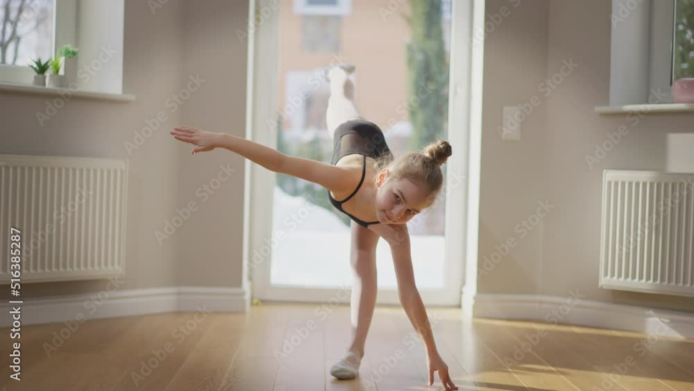 Motivated teen girl standing on one leg training gymnastics indoors in slow motion. Wide shot portrait of Caucasian inspired teenage gymnast exercising. Balance and motivation concept Motivated teen girl standing on one leg training gymnastics indoors in slow motion. Wide shot portrait of Caucasian inspired teenage gymnast exercising. Balance and motivation concept