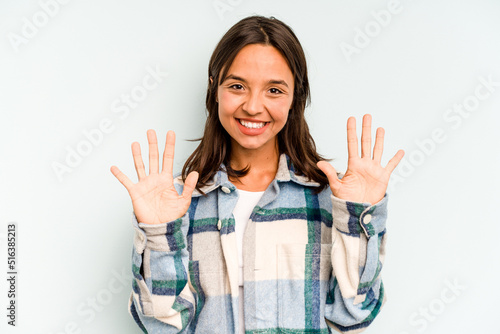 Young hispanic woman isolated on blue background blink at the camera through fingers, embarrassed covering face.