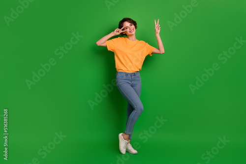 Full size portrait of gorgeous nice lady arms fingers demonstrate v-sign near eye isolated on green color background