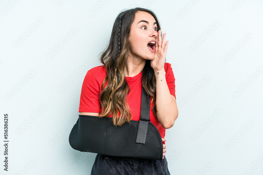 Young caucasian woman with broke hand isolated on blue background shouting and holding palm near opened mouth. Young caucasian woman with broke hand isolated on blue background shouting and holding palm near opened mouth.