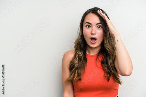 Young caucasian woman isolated on white background shouts loud, keeps eyes opened and hands tense.