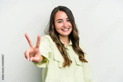 Young caucasian woman isolated on white background joyful and carefree showing a peace symbol with fingers.
