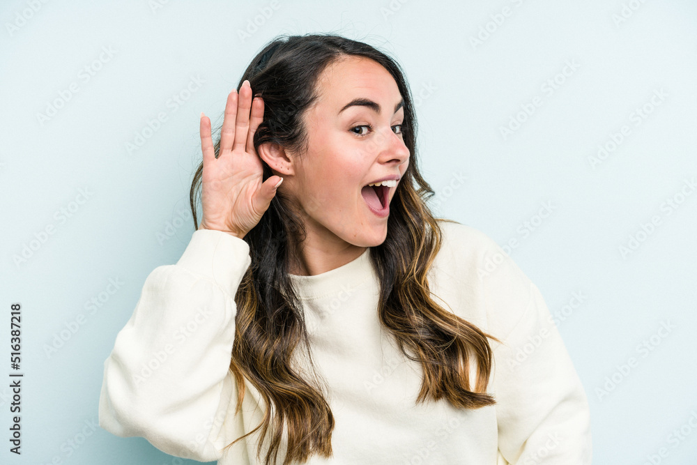 Young caucasian woman isolated on blue background trying to listening a gossip. Young caucasian woman isolated on blue background trying to listening a gossip.