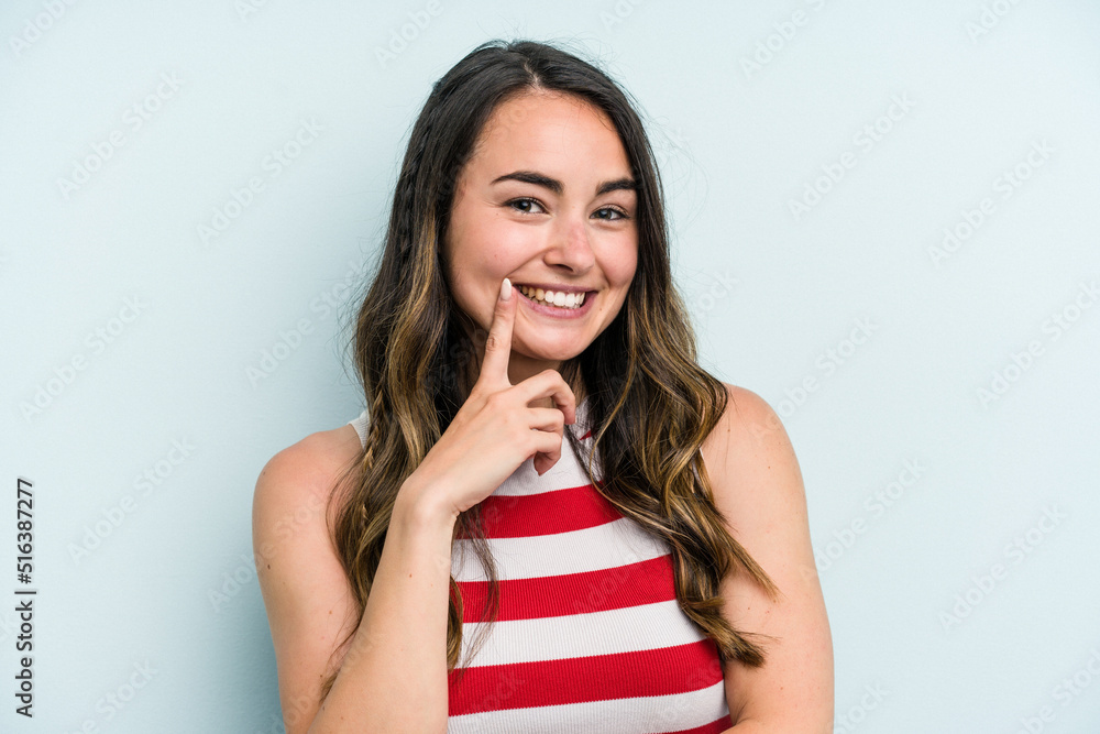 Young caucasian woman isolated on blue background smiling happy and confident, touching chin with hand. Young caucasian woman isolated on blue background smiling happy and confident, touching chin with hand.