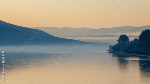 Blurred morning landscape on a foggy river in sepia colors