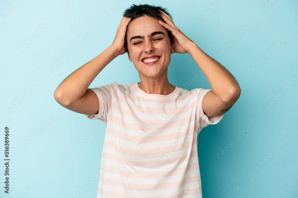 Young caucasian woman isolated on blue background laughs joyfully keeping hands on head. Happiness concept. Young caucasian woman isolated on blue background laughs joyfully keeping hands on head. Happiness concept.