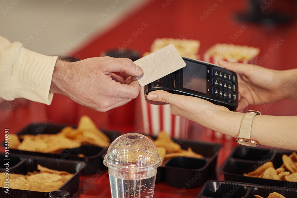 © Seventyfour - Close-up of buyer paying with credit card for his popcorn with seller reaching terminal to him